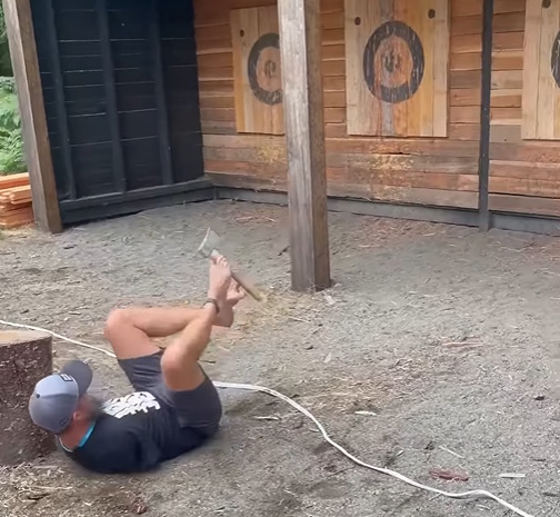 Daniel throwing a hatchet with his feet